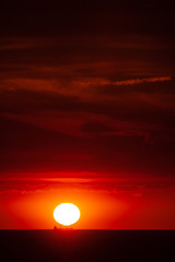 Cargo ship on the sea in sunset with  cloud formations in red light