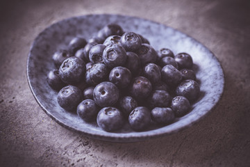 Organic Blueberries in Blue Plate on Dark Background