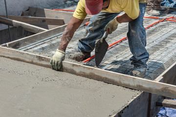 Bricklayer leveling a cement roof. Stretching out to smooth the casted concrete mix  