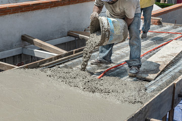 Pouring concrete at a construction site. Filling a rooftop with cement over the pipelines