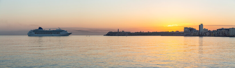 Beautiful Panoramic view of a Big Cruise Ship arriving to the Old Havana City, Capital of Cuba, during a colorful cloudy sunrise.