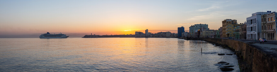 Fototapeta na wymiar Beautiful Panoramic view of a Big Cruise Ship arriving to the Old Havana City, Capital of Cuba, during a colorful cloudy sunrise.