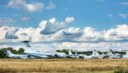 Old russian aircrafts at the abandoned aerodrome in summertime. Cemetery of large and small aircraft near the runway