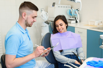 Obraz premium The male dentist speaks with happy female patient.