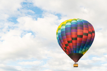 Two hot air balloons floating under vibrant blue sky with puffy white clouds