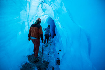 Two glacier guides walking into a large ice cave in Alaska.