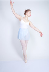 cute caucasian girl in ballet clothes learning to be a ballerina on a white background in the Studio. plus size young woman dreams of being a dancer.