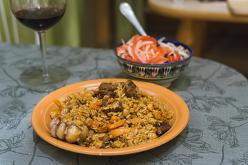 pilaf with red wine in a glass and a salad of tomato and onion. Oriental dish of rice and meat