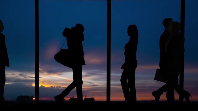 The silhouette of kissing couple and walking people near the airport window