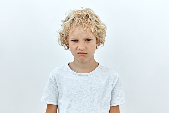 Annoyed and upset emotion. Headshot portrait of little blonde child boy against white background