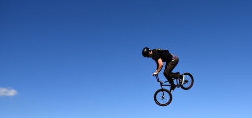 Hoch in den blauen Himmel fliegender BMX-Biker