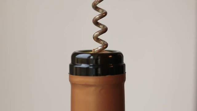 screwing the corkscrew into the wine bottle cork