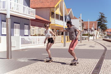 Young active couple enjoying a summer sunny day skateboarding