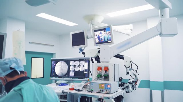 Modern medical equipment in the light operating room. Surgeons are performing an operation to a patient on the background of contemporary furnishing in a surgery cabinet.