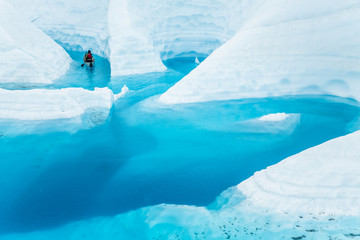 Ice climber boating through winding canyons flooded by glacier water of the Matanuska Glacier in...