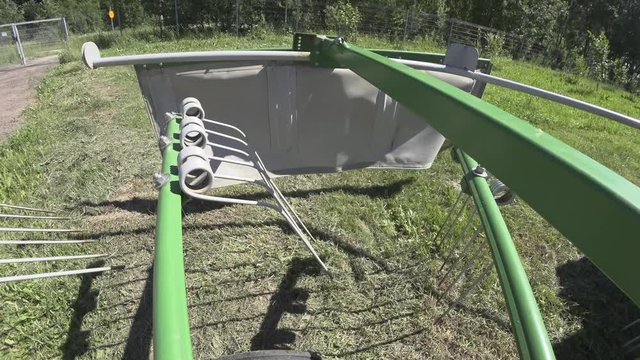 Drying hay turning with a rotor tractor rake close-up camera on the frame