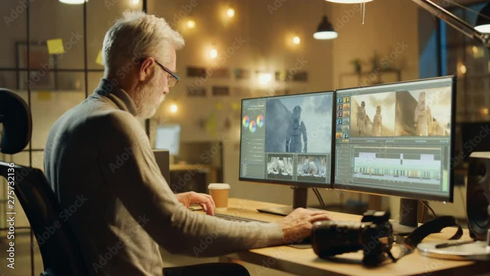 Poster evening in creative office: professional middle aged videographer works on desktop computer, doing f
