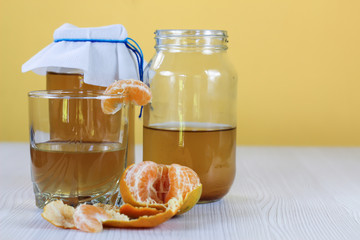 fermented drink, jun tea healthy natural probiotic in a glass jar, with a glass and tangerine ready to drink