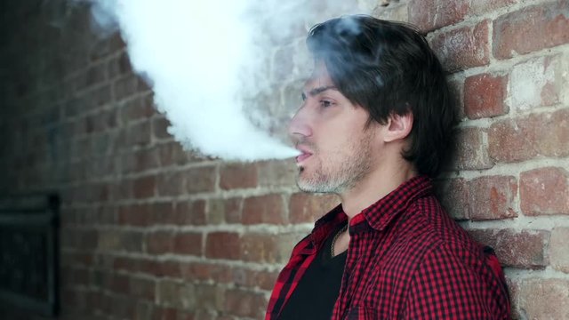 Stylish man in a city. Elegant male use the electronic cigarette