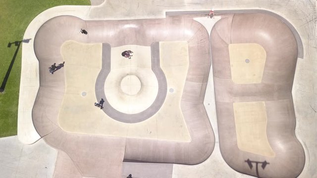 Adolescent skater group shows off her tricks on a skate park in Australia. Sunny drone shot in top view