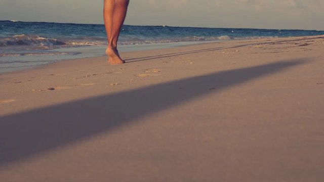 Beautiful woman legs, walking along the beach. Leaving footprints on sand