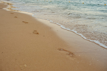 Footprints of human feet on the sand near the water on the beach
