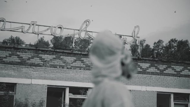 The scientist put on a respirator and a protective robe. a student checks the ecology on the background of an abandoned building. Close-up of a respirator. ecology rescue on black and white video.