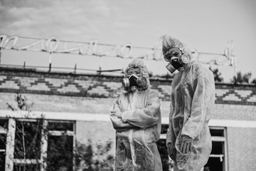Two scientists put on a respirator and a radiation protective suit. Stern look into the camera from...