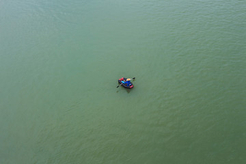 Aerial shot of a quiet green lake with a kayaking in the middle of the water