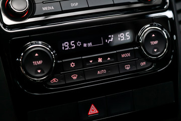 Black detail with the air conditioning button, the dashboard with information about temperature inside a car. modern car interior: parts, buttons, knobs..