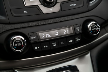 Black detail with the air conditioning button, the dashboard with information about temperature inside a car. modern car interior: parts, buttons, knobs..