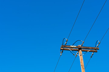 High voltage wooden utility pole (column or post) with parallel single-circuit lines in the blue sky