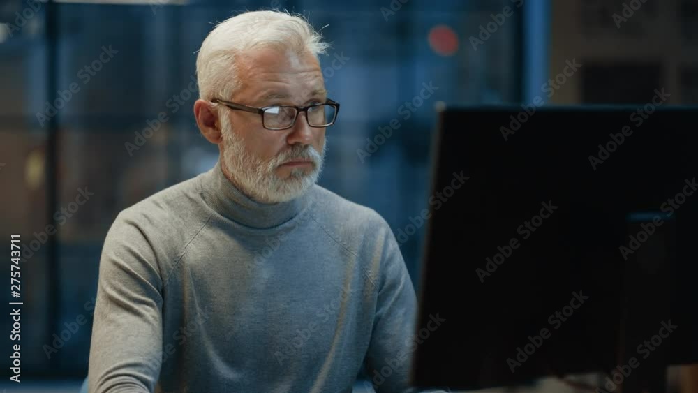 Poster portrait of the handsome and successful middle aged bearded businessman working at his desk using la