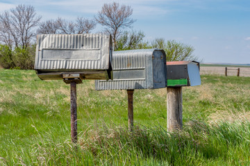 A row of three old metal farmer’s mailboxes on the prairies in rural Saskatchewan, Canada