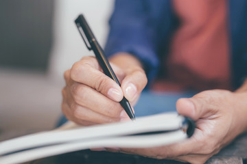 close up hand business woman are sitting using pen writing Record Lecture note pad into the book on the table wood. © methaphum