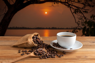 cennamon and roasted coffee in spoon with white coffe cup on wooden desk on landscape view