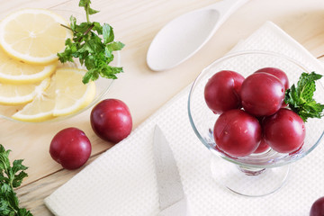 plums lie in a glass cream bowl on the table, lemon cut into slices, fresh mint leaves, healthy foods, dietary berries and fruits,