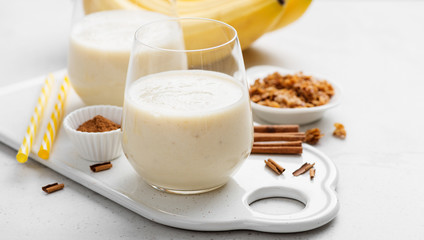 Obraz na płótnie Canvas Banana smoothie in glass with granola and cinnamon for healthy breakfast.