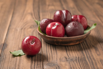 Fototapeta na wymiar Ripe plums in a bowl and on a wooden table.
