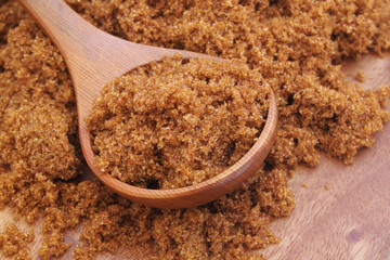 Dark brown sugar with spoon   on wooden background