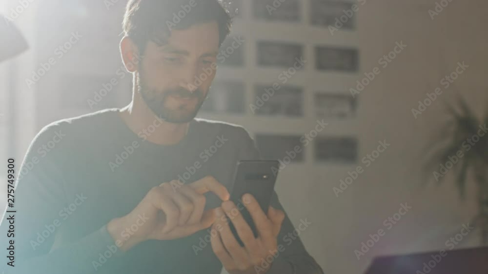 Poster professional creative man sitting at his desk in home office studio using smartphone man using mobil