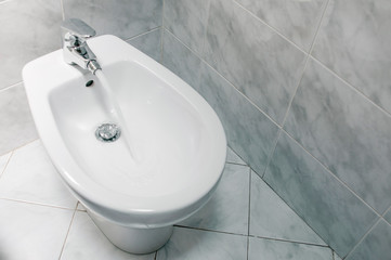 Fototapeta premium Bidet with running water top down, with copy space.