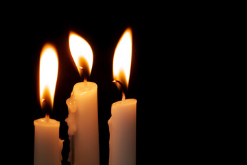 Burning candles on black background with copy space for message. Funeral and memorial symbol.