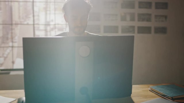 Creative Designer Sitting at His Desk in Office Studio Working on a Desktop Computer with Smartphone Software Development Application on Screen. Web, App Developer. 360 Degree Tracking Arc Shot
