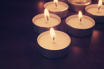 Burning candles on table in darkness. Romance, celebration and memorial symbol.