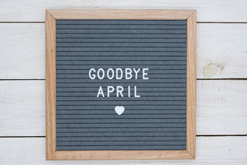 text in English goodbye April and a heart sign on a gray felt Board in a wooden frame