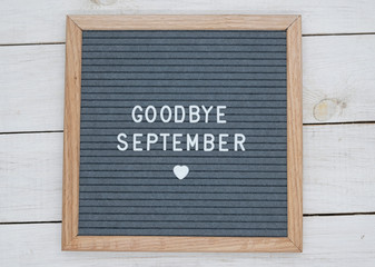 text in English goodbye September and a heart sign on a gray felt Board in a wooden frame