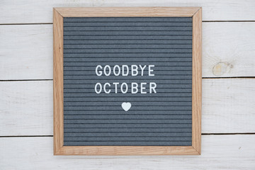 text in English goodbye October and a heart sign on a gray felt Board in a wooden frame