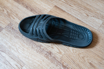 One black male slipper on the floor.