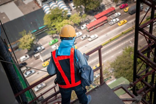 Construction workers on high-rise buildings are looking down to the floor below, a dress that is safe from construction work with a helmet and reflective jacket.
